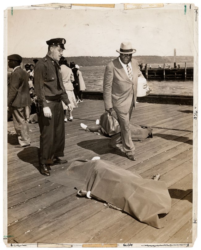 Weegee (Arthur Fellig) (American, 1899-1968) 'Untitled [Police officer and lodge member looking at blanket-covered body of woman trampled to death in excursion-ship stampede, New York]' August 18, 1941