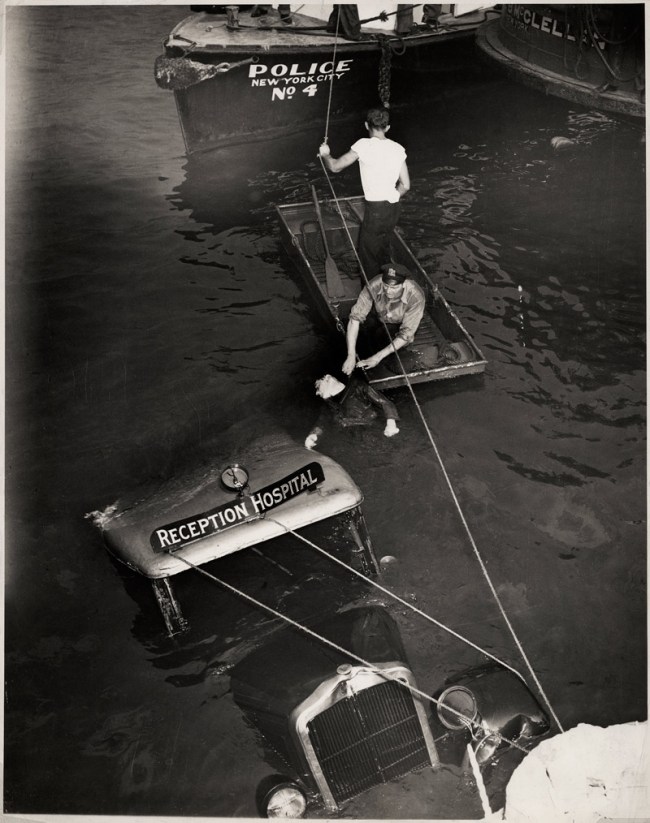 Weegee (Arthur Fellig) (American, 1899-1968) 'Untitled [Police officer and assistant removing body of Reception Hospital ambulance driver Morris Linker from East River, New York]' August 24, 1943