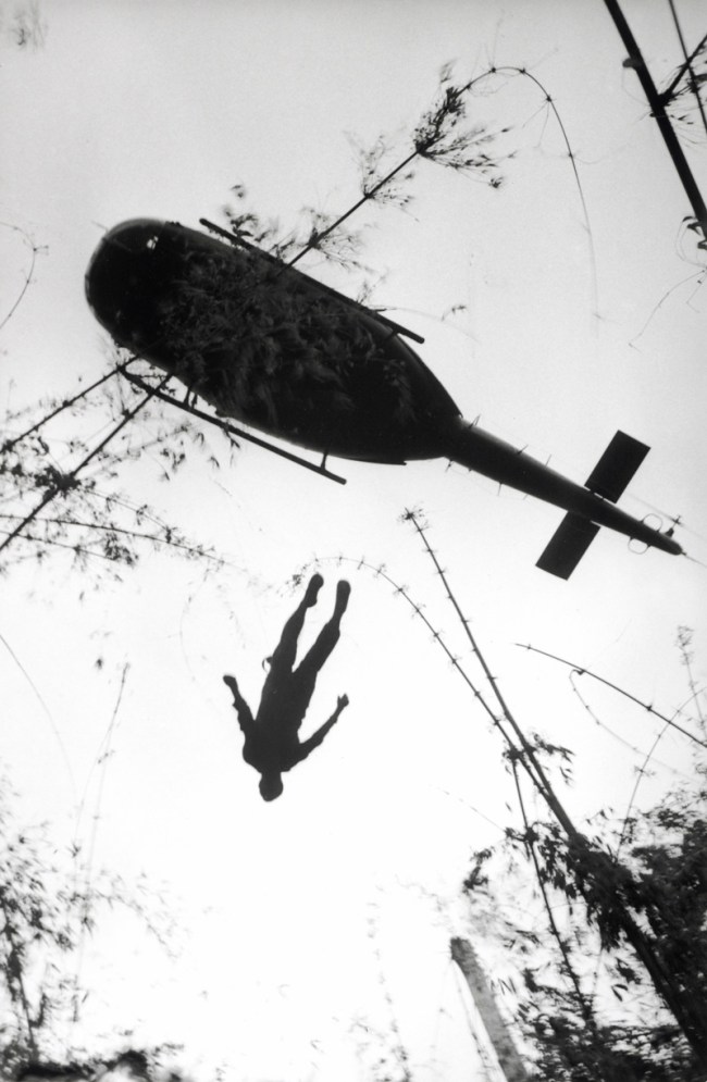 Henri Huet (French, 1927-1971) 'The body of an American paratrooper killed in action in the jungle near the Cambodian border is raised up to an evacuation helicopter, Vietnam' 1966