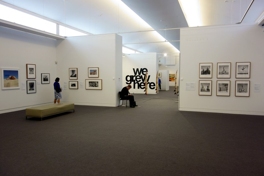 Installation view of the exhibition 'On the beach' at the Mornington Peninsula Regional Art Gallery showing at far left, Anne Zahalka's 'The sunbather #2' (1989) and, at right, a selection of George Caddy's beachobatics photographs