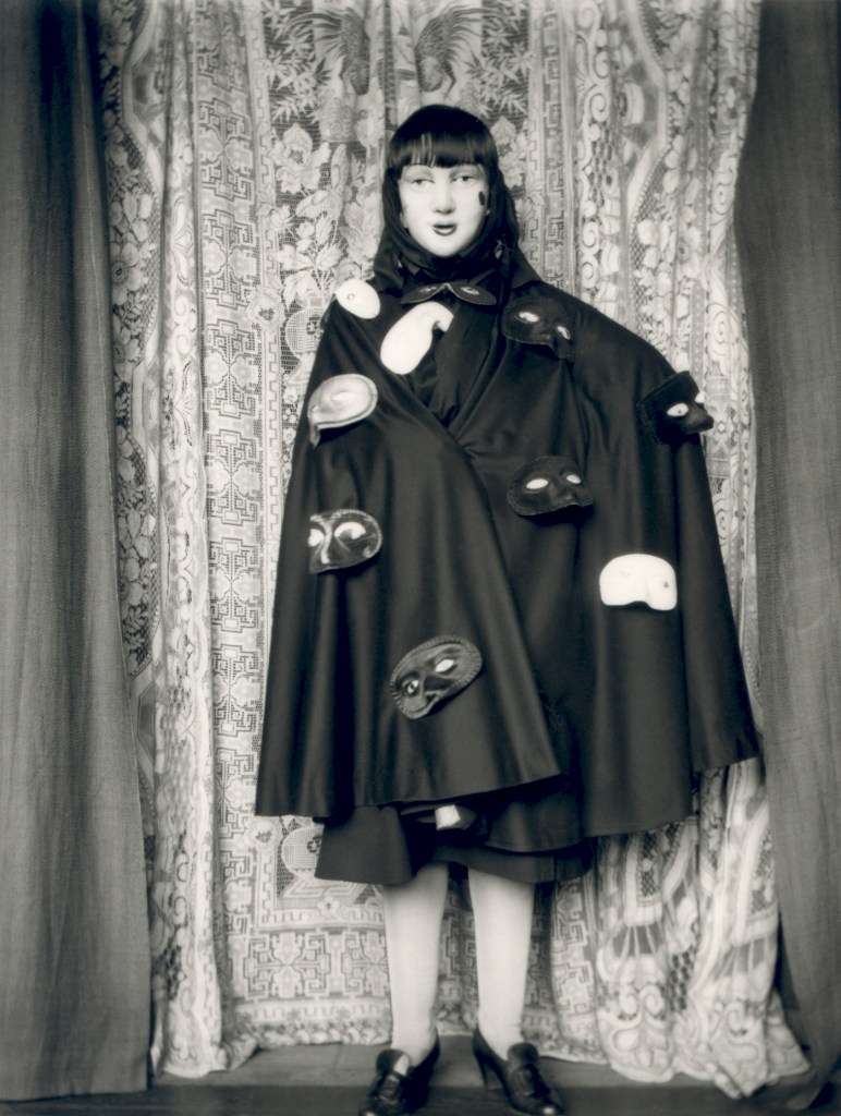 Claude Cahun (French, 1894-1954) 'Self-portrait (full length masked figure in cloak with masks)' 1928