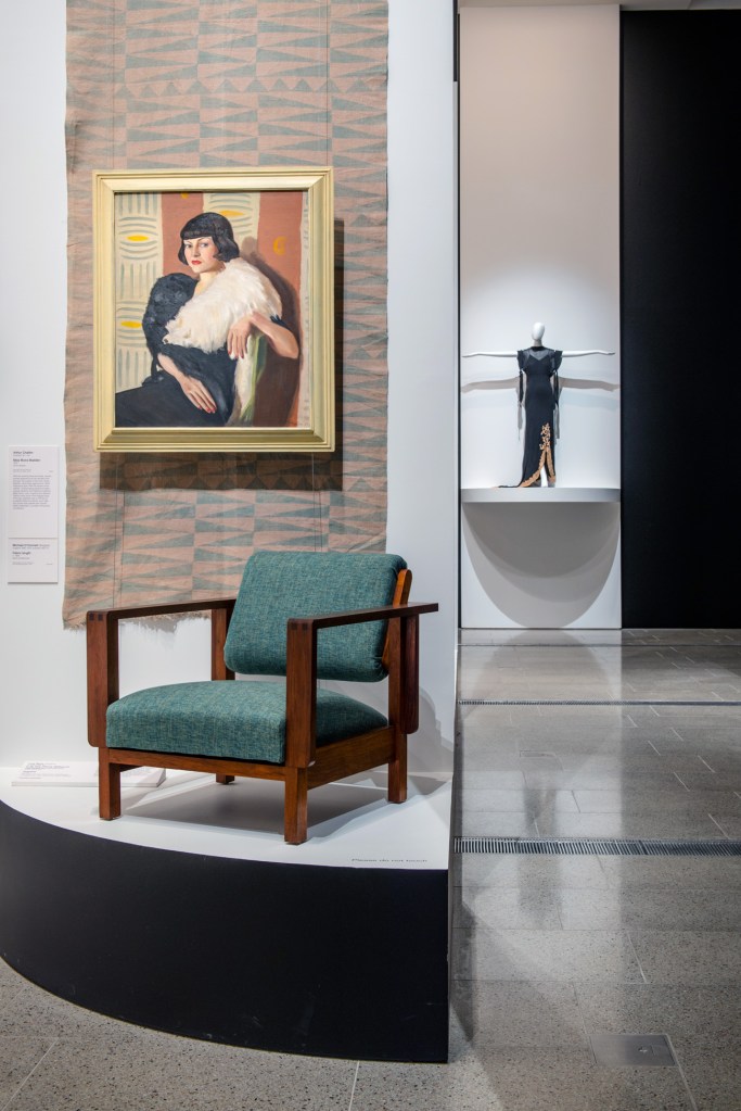 Installation view of the exhibition 'Brave New World: Australia 1930s' at NGVA with Arthur Challen's 'Miss Moira Madden' above chair