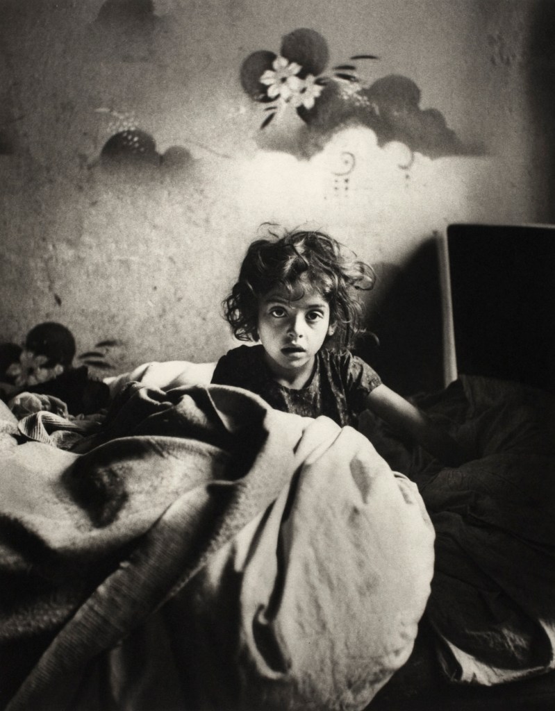 Roman Vishniac (America born Russia, 1897-1990) 'Sara, sitting in bed in a basement dwelling, with stencilled flowers above her head, Warsaw' c. 1935-1937