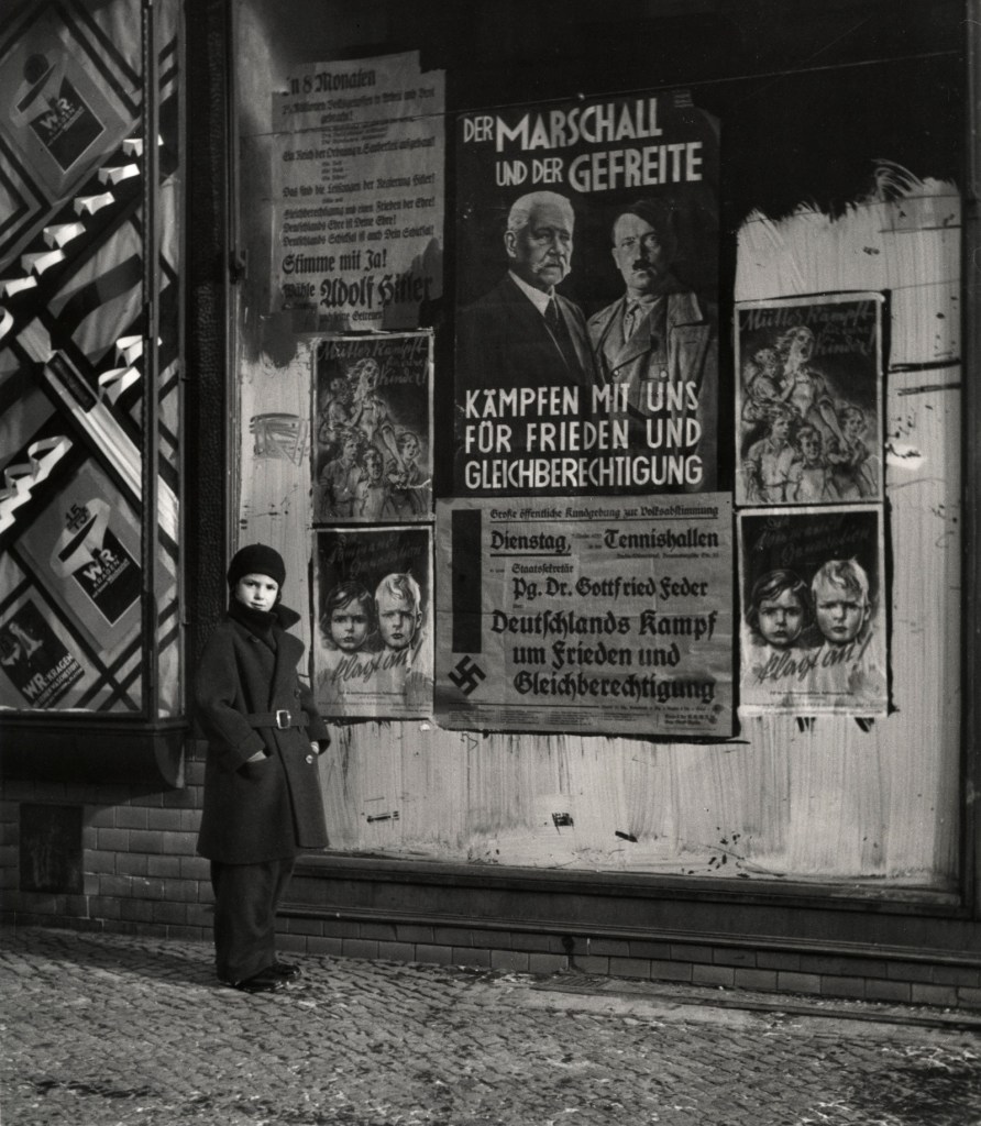 Roman Vishniac (America born Russia, 1897-1990) 'Vishniac's daughter Mara posing in front of an election poster for Hindenburg and Hitler' 1933
