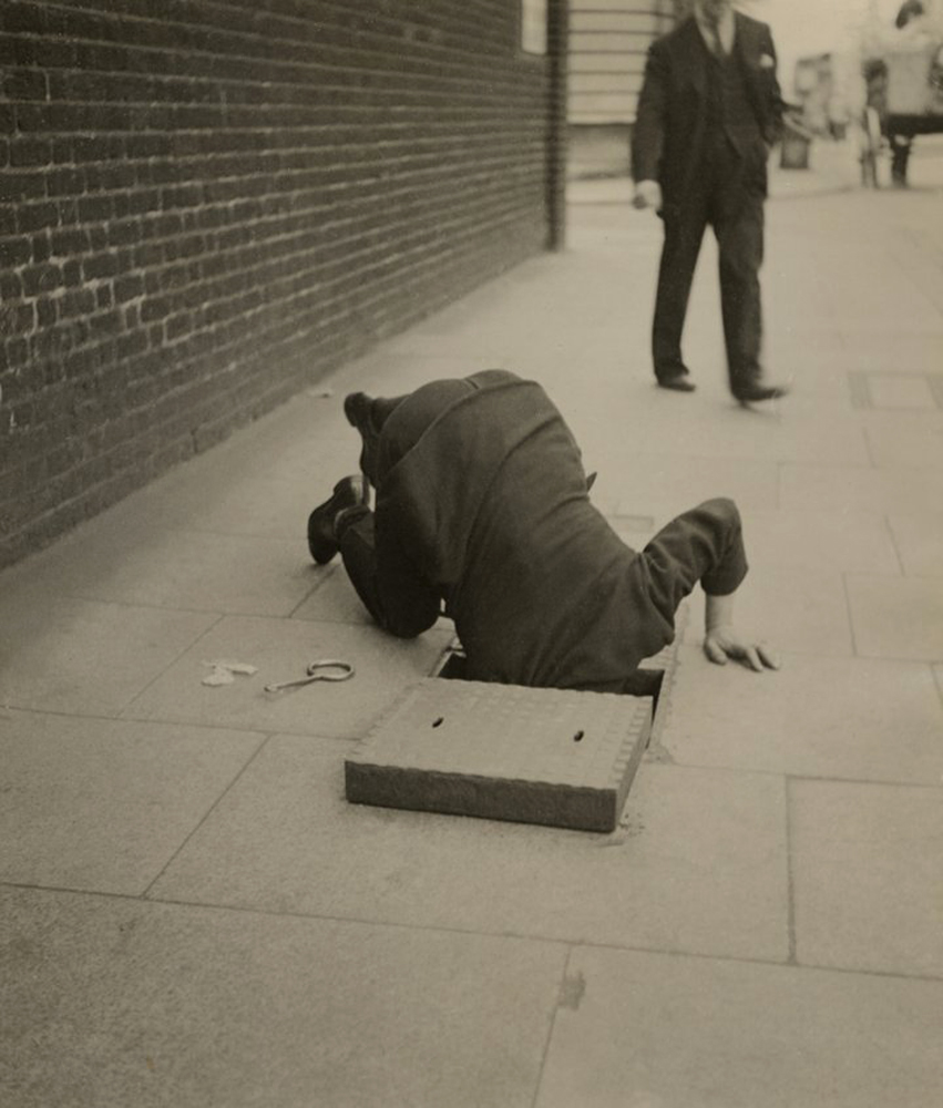 Dora Maar (French, 1907-1997) 'Man looking inside a sidewalk inspection door, London' c. 1935 Dora Maar (French, 1907-1997) 'Man looking inside a sidewalk inspection door, London' c. 1935
