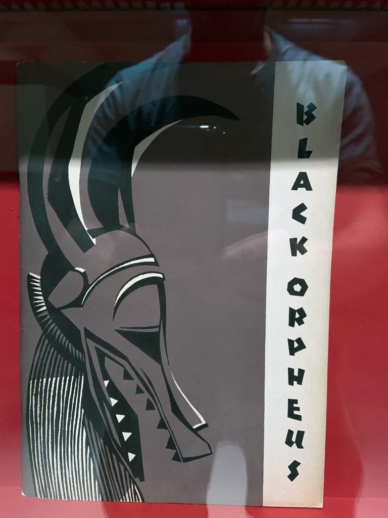 Installation view of the exhibition 'Into the Night: Cabarets and Clubs in Modern Art' at the Barbican Art Gallery showing some of the publishing output of the Mbari clubs Installation view of the exhibition 'Into the Night: Cabarets and Clubs in Modern Art' at the Barbican Art Gallery showing some of the publishing output of the Mbari clubs