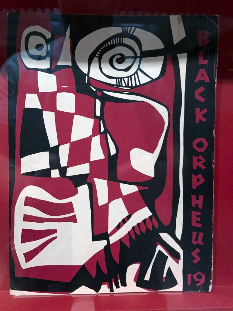 Installation view of the exhibition 'Into the Night: Cabarets and Clubs in Modern Art' at the Barbican Art Gallery showing some of the publishing output of the Mbari clubs Installation view of the exhibition 'Into the Night: Cabarets and Clubs in Modern Art' at the Barbican Art Gallery showing some of the publishing output of the Mbari clubs