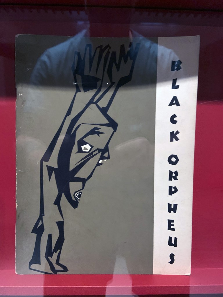 Installation view of the exhibition 'Into the Night: Cabarets and Clubs in Modern Art' at the Barbican Art Gallery showing some of the publishing output of the Mbari clubs Installation view of the exhibition 'Into the Night: Cabarets and Clubs in Modern Art' at the Barbican Art Gallery showing some of the publishing output of the Mbari clubs