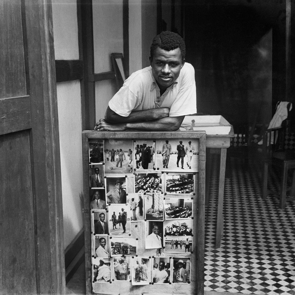 James Barnor (Ghanian, b. 1929) 'Portrait of James Barnor in front of some of his photographs, Accra' 1957 from the exhibition 'James Barnor: Accra/London – A Retrospective' at the Serpentine North Gallery, London, May - Oct, 2021