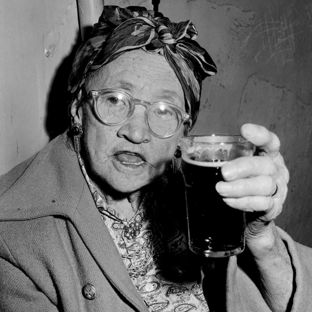 Mervyn Bishop (Australian, b. 1945) 'A woman drinks a pint of beer in a Glebe pub on the eve of its closing' 1967