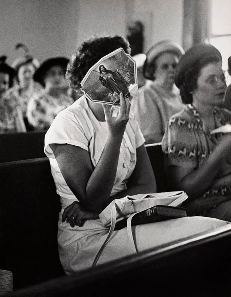 Marion Palfi (American born Germany, 1907-1978) 'Untitled (Woman in church holding a fan over her face)' 1949