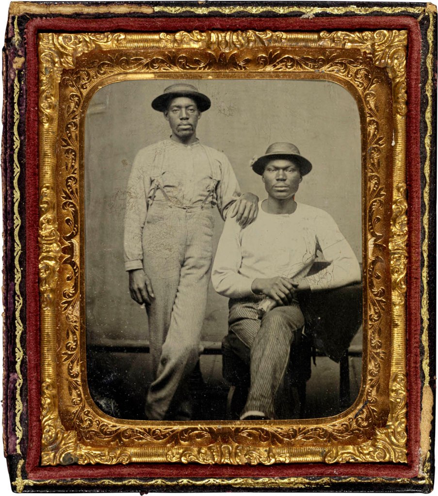 Unidentified photographer (American). 'Untitled [Two Men in Work Clothes, Wearing Hats, One Standing, One Seated]' c. 1880 from the exhibition 'Called to the Camera: Black American Studio Photographers' at the New Orleans Museum of Art (NOMA), Sept 2022 - Jan 2023