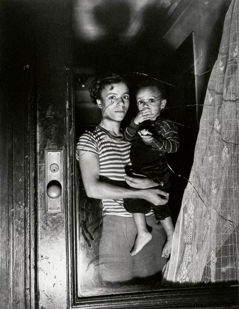 Weegee (Arthur Fellig) (American born Ukraine, 1899-1968) '[Mrs. Bernice Lythcott and son looking through window shattered by rock-throwing hoodlums, Harlem, New York]' October 18, 1943