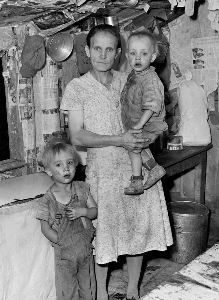 Russell Lee (American, 1903-1986) 'Mrs. John Whitehead, wife of miner, and two of her children (or grandchildren) in the kitchen of her three room house. Mr. and Mrs. John Whitehead, their six children and six grandchildren live here. This house, built on company owned land was built by Mr. Whitehead's half brother at no expense for materials or labor to the company; the builder (half brother) was to receive the use of the house rent-free for three years and at the end of this period the ownership of the house would revert to the company. The brother moved away at the end of one year, receiving no cash settlement from the company. The house now rents for $6 monthly. It has no running water, no electricity, access is over a mountain trail; there are three rooms. Coleman Fuel Company, Red Bird Mine, Field, Bell County, Kentucky' (Original Caption) August 31, 1946 (detail)