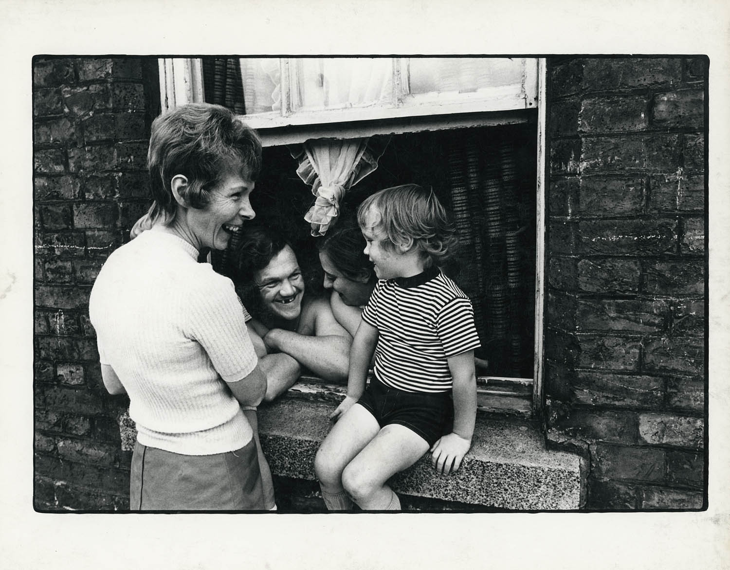 Paul Trevor (English, b. 1947) 'Wapping family at window' 1973 from the exhibition 'A World Apart: Photographing change in London's East End 1970-76' at Four Corners, Oct - Dec, 2025 Paul Trevor (English, b. 1947) 'Wapping family at window' 1973 from the exhibition 'A World Apart: Photographing change in London's East End 1970-76' at Four Corners, Oct - Dec, 2025