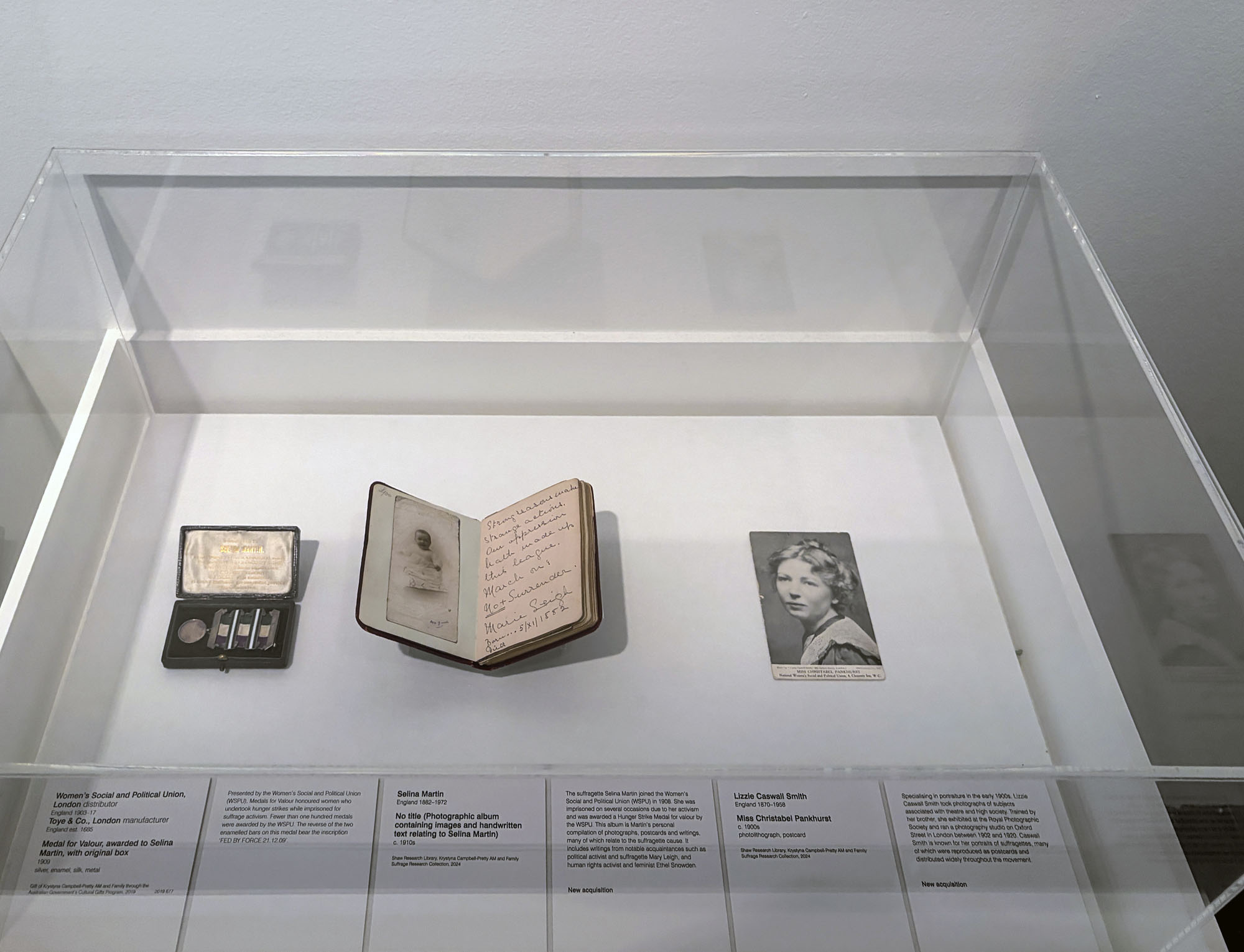 Installation view of the exhibition 'Women Photographers 1900-1975: A Legacy of Light' at NGV International, Melbourne, November 2025 - May 2026 showing from left to right, Woman's Social and Political Union (distributor) Toye & Co. (manufacturer) 'Medal for Valour, awarded to Selina Martin, with original box' (1909); Selina Martin (England, 1882-1972) 'No title (Photographic album containing images and handwritten text relating to Selina Martin)' (c. 1910); Lizzie Casual Smith (England, 1870-1956) 'Miss Christabel Pankhurst' (c. 1900s) Installation view of the exhibition 'Women Photographers 1900-1975: A Legacy of Light' at NGV International, Melbourne, November 2025 - May 2026 showing from left to right, Woman's Social and Political Union (distributor) Toye & Co. (manufacturer) 'Medal for Valour, awarded to Selina Martin, with original box' (1909); Selina Martin (England, 1882-1972) 'No title (Photographic album containing images and handwritten text relating to Selina Martin)' (c. 1910); Lizzie Casual Smith (England, 1870-1956) 'Miss Christabel Pankhurst' (c. 1900s)